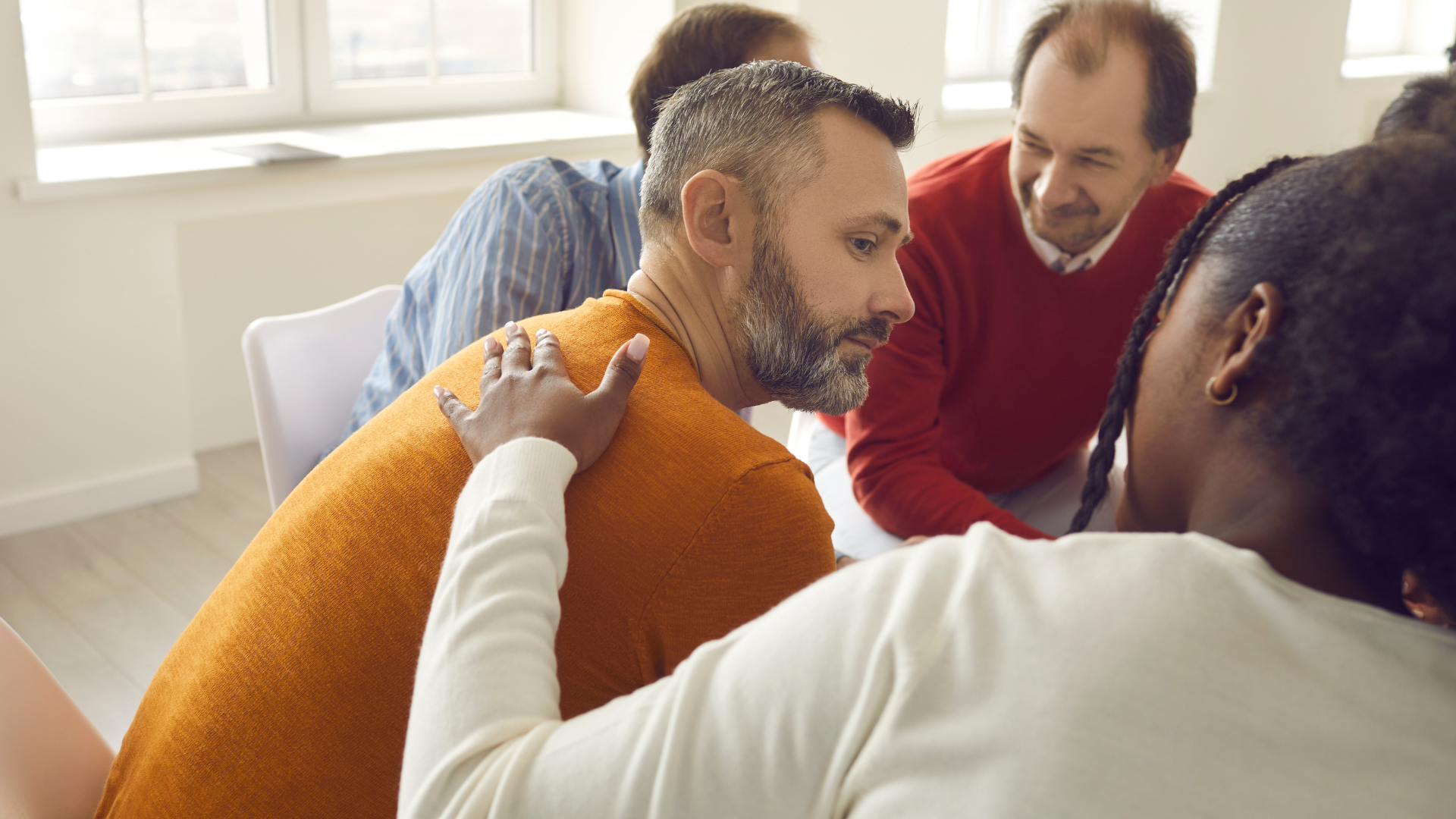 Woman placing her hand onto a man's back in a supportive manner.