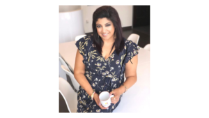 Smiling woman in floral dress holding coffee mug