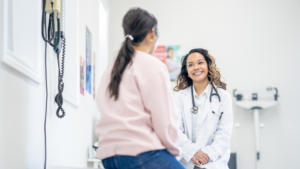 Smiling doctor consulting patient in exam room