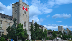 Stone campus clock tower with Canadian flag