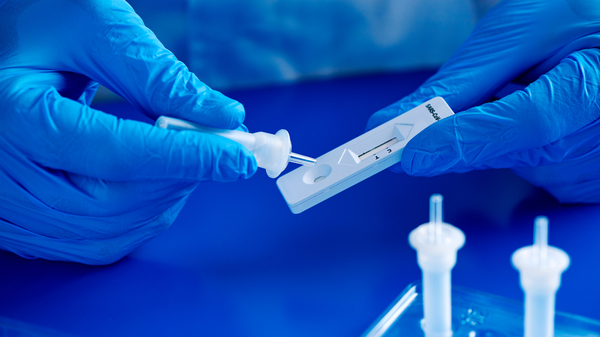 A healthcare professional wearing blue gloves handling a rapid test device, emphasizing the importance of quick and accurate testing for infectious diseases during the cold and flu season.