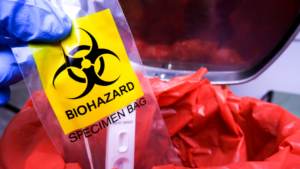 Gloved hand holding biohazard specimen bag