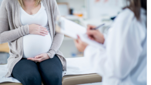 Pregnant woman consulting doctor in clinic