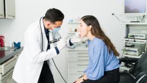 Doctor examining patient's throat with medical device