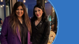 Two women smiling indoors at evening event