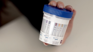 Hand holding urine drug test cup