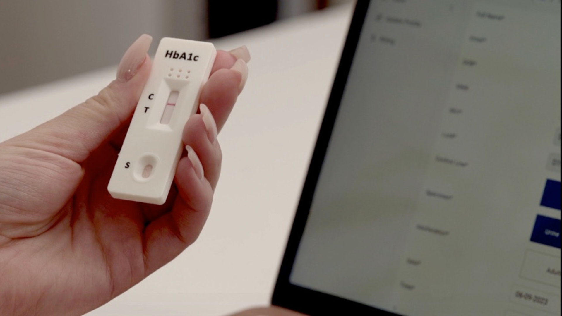 Hand holding an HBA1C Rapid Test, using a digital rapid testing software.