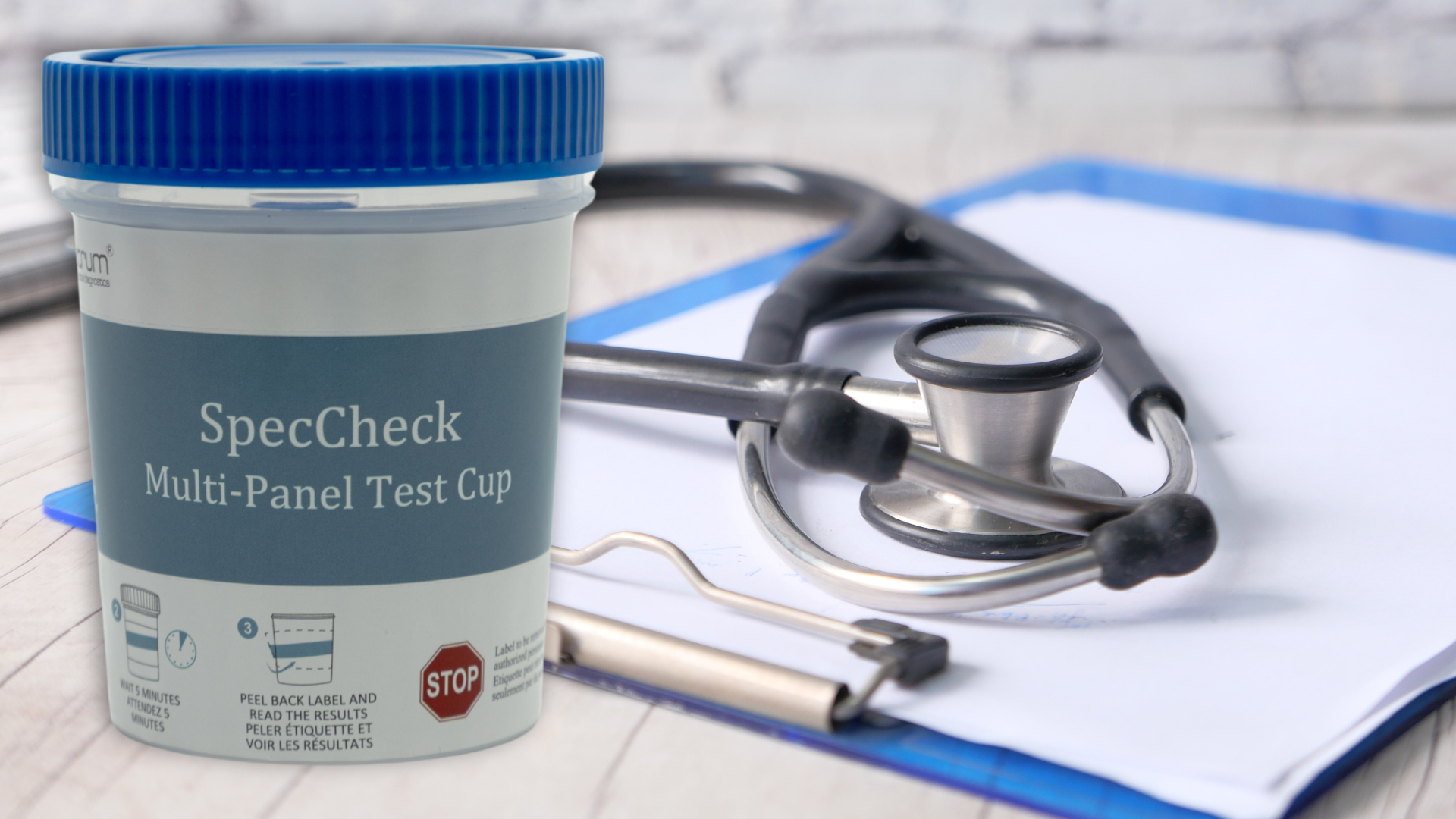 SpecCheck Multi-Panel Drug Test with a Blue Lid in front of a medical clipboard with a stethoscope sat on top of it.